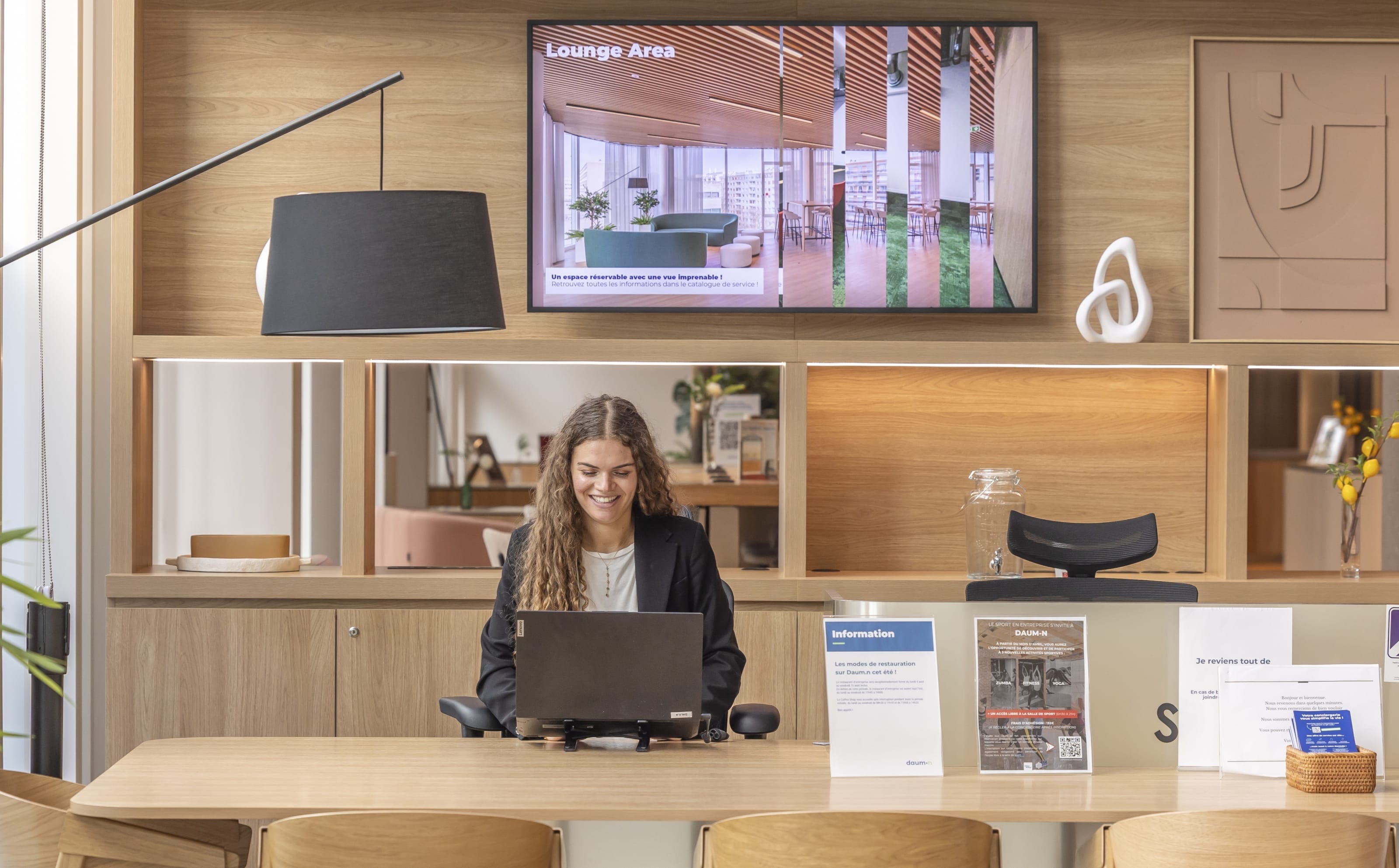 Femme devant son ordinateur à l'accueil d'un immeuble