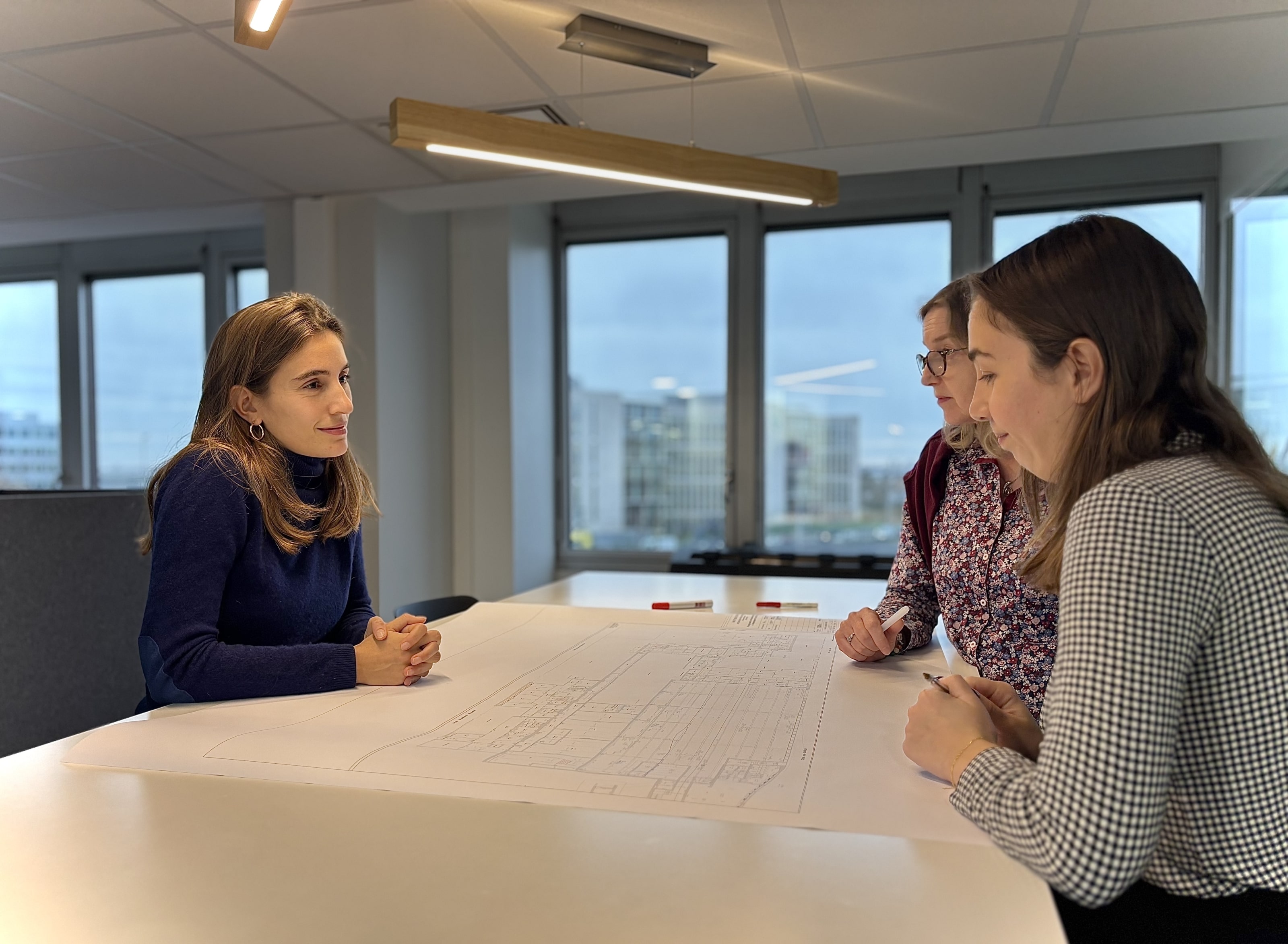 3 femmes autour d'un plan en réunion de travail
