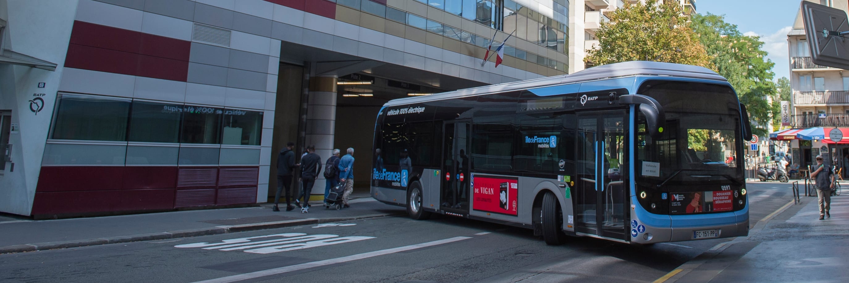 Bus articulé circulant devant l’entrée d’un centre de bus en milieu urbain