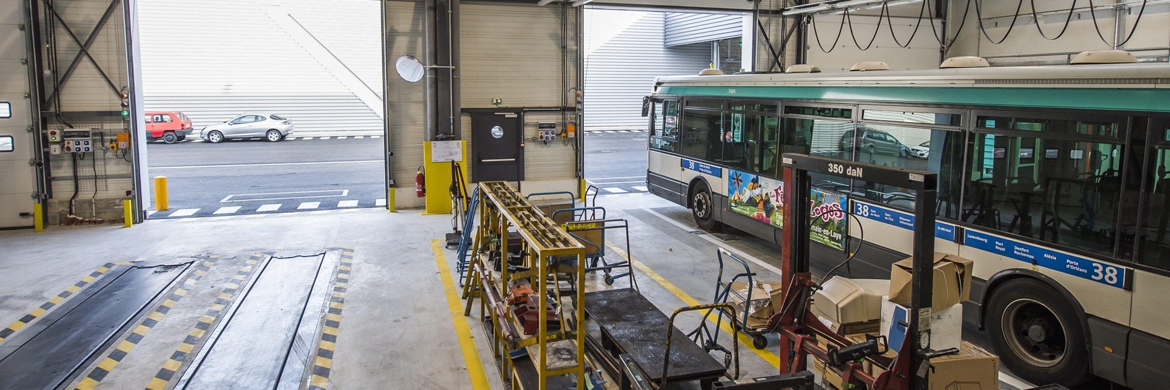 Zone de maintenance intérieure d’un centre de bus avec un véhicule et des équipements techniques